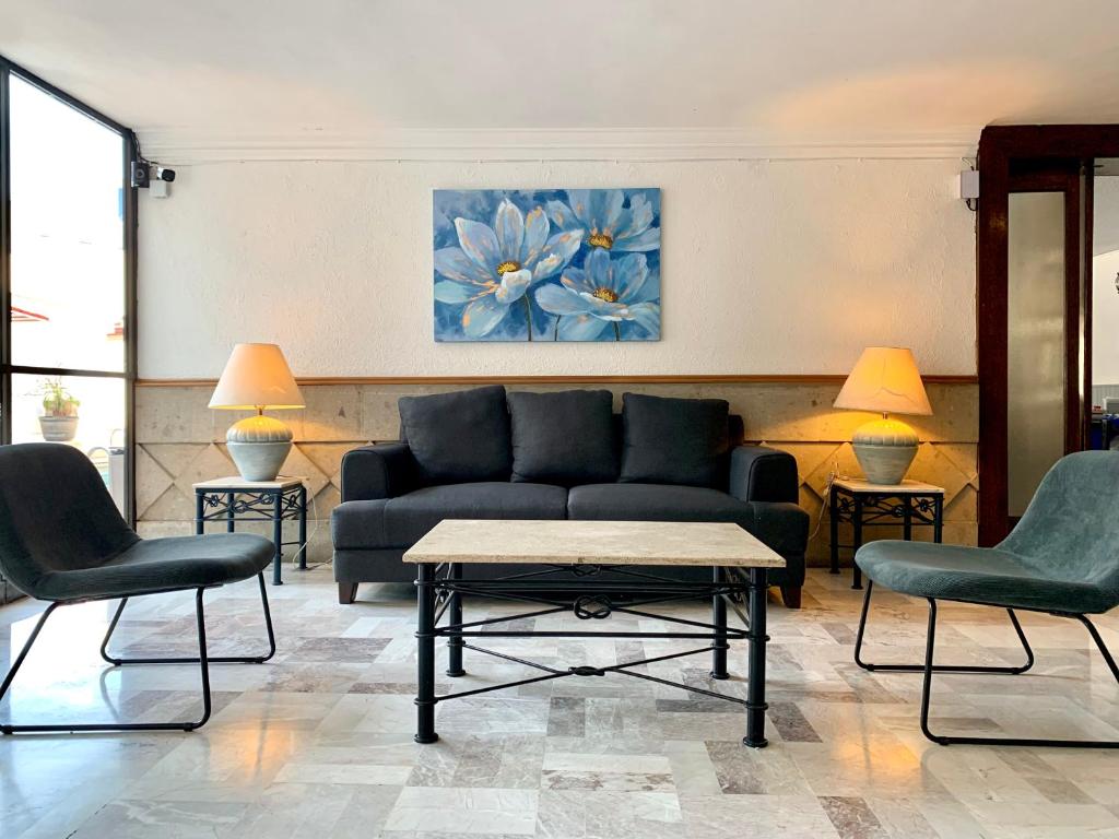 sala de estar con sofá y 2 sillas en Hotel Beddo Express Querétaro, en Querétaro