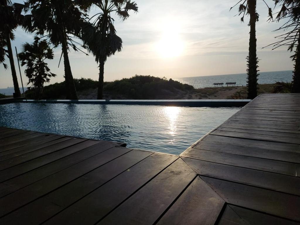 a view of a pool with palm trees and the ocean at Majestic Beach Retreat in Kalpitiya