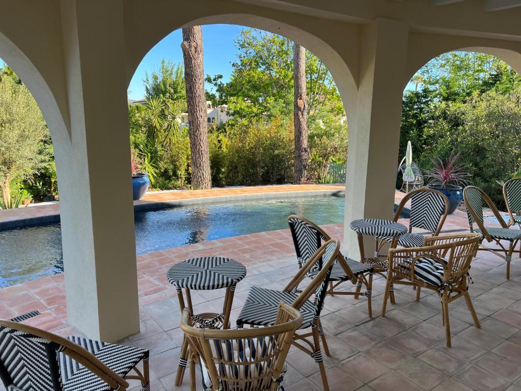 a patio with chairs and tables and a swimming pool at Maison d'Orange - La Pinede in Saint-Tropez