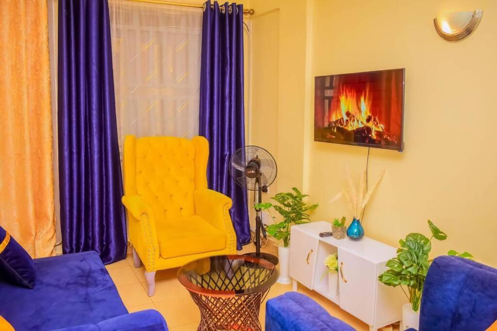 a living room with a blue couch and a yellow chair at Modern one bedroom742333980 in Kisumu