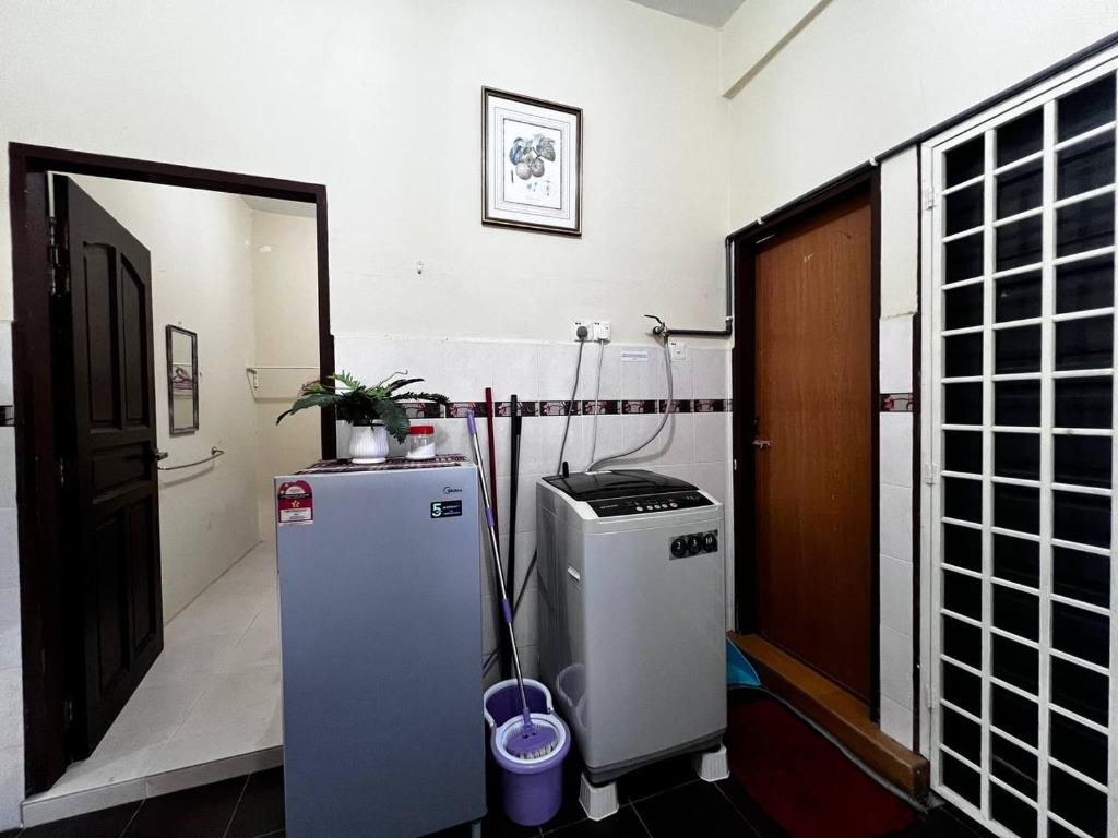Zimmer mit kleinem Kühlschrank und Tür in der Unterkunft Dhiaa Homestay D Jembal in Kuala Terengganu