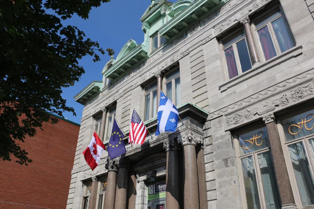 um edifício com bandeiras na lateral em Hotel Auberge Manoir Ville Marie em Montreal