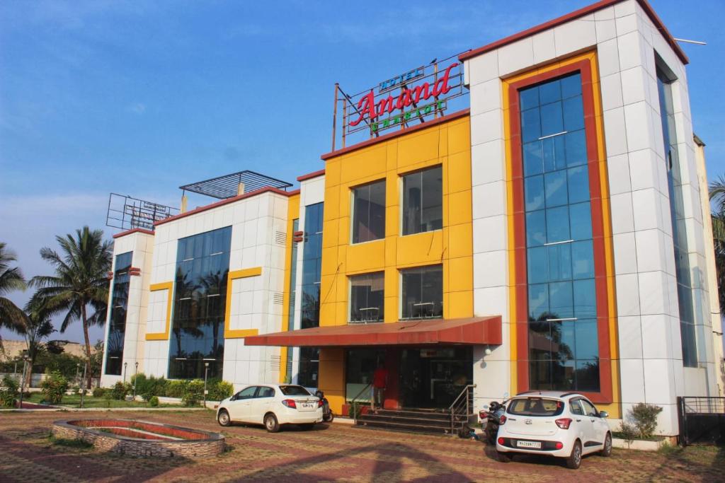 dos coches estacionados frente a un edificio en HOTEL ANAND, en Ratnagiri