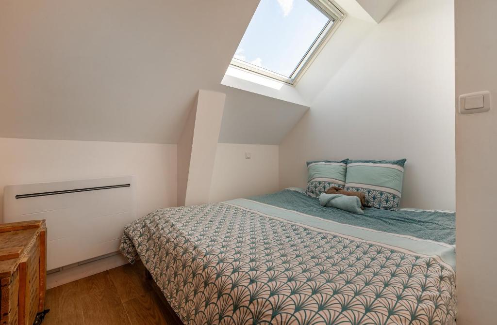 1 dormitorio con 1 cama en un ático con ventana en Gwenn Ha Du, en Merlevenez