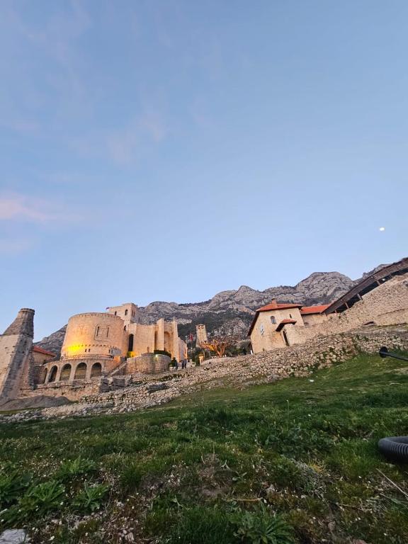 an old building on a hill with a green field at Castle - inside,Voga Guesthause in Krujë