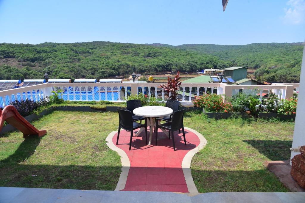 a patio with a table and chairs in a yard at Mauli Villa, 4BHK Villa in Mahabaleshwar at Venna Lake in Mahabaleshwar