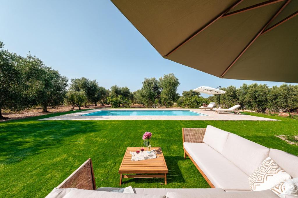 um quintal com uma piscina, uma mesa e um guarda-sol em HelloApulia Trulli il Rifugio dei Messapi em Ceglie Messapica
