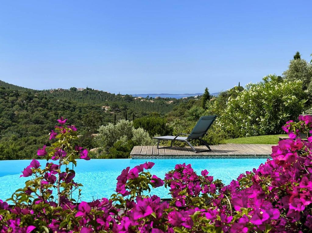 - une piscine avec des fleurs violettes et une chaise dans l'établissement Villa CORAIL privée et climatisée pour 10 personnes avec piscine et superbe vue mer et collines à La Londe-les-Maures, à La Londe-les-Maures
