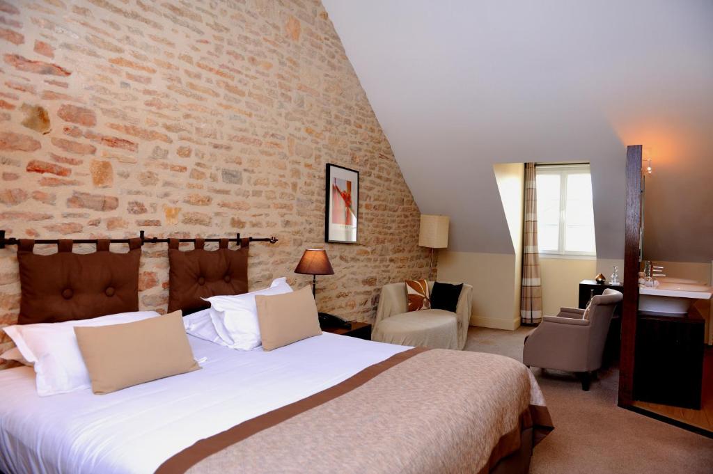 - une chambre avec un grand lit et un mur en briques dans l'établissement The Originals Boutique, Hôtel de la Paix, Beaune (Qualys-Hotel), à Beaune