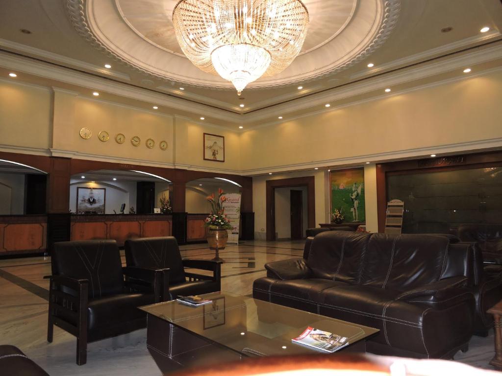 a lobby with a couch and chairs and a chandelier at Hotel PLR Grand in Tirupati