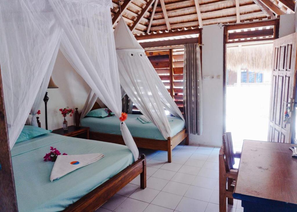 ネンブララにあるAnugerah Surf & Diveのベッドルーム(蚊帳付きベッド2台付)