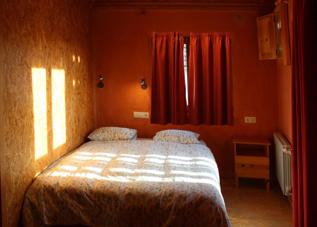 1 dormitorio con 1 cama y una ventana con cortinas rojas en La Choza de Trasmulas, en Trasmulas