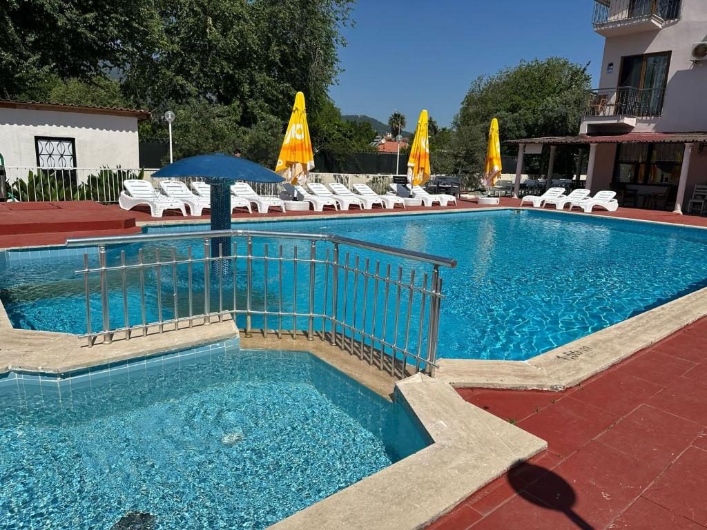 a large swimming pool with chairs and an umbrella at Dalyan Nehir suit hotel in Dalyan