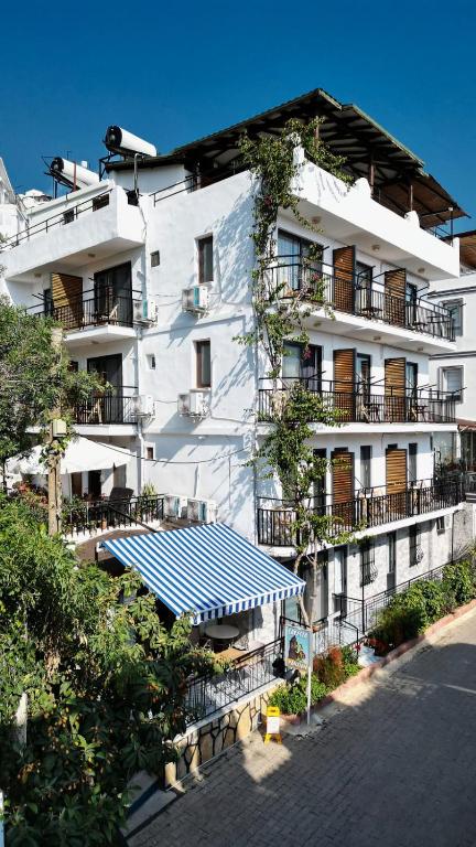 a white building with a blue awning in front of it at CARETTA PANSİYOn in Kaş