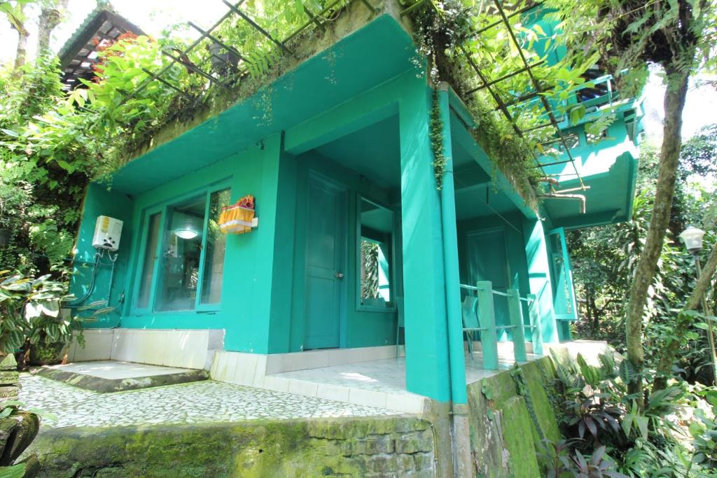 Belvilla 93915 Bamboo Villa Near Central Ubud في أوبود: منزل أخضر مع باب أمامى أزرق