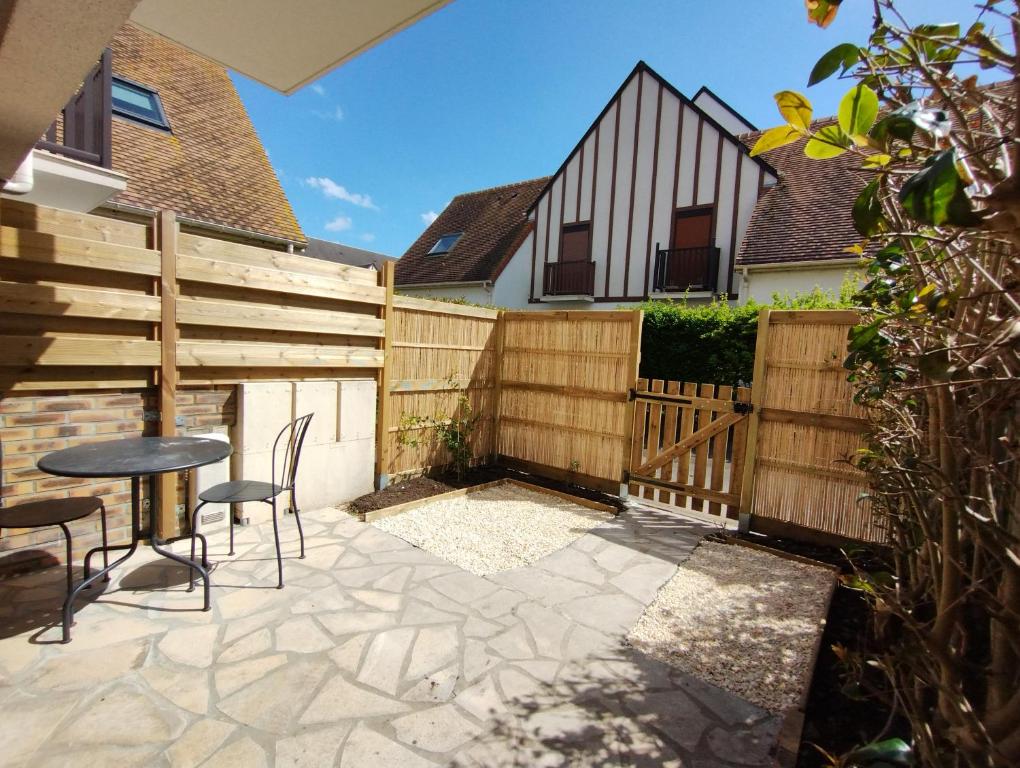 une terrasse avec une clôture en bois, une table et des chaises dans l'établissement Studio plain pied avec terrasse tout proche mer, à Courseulles-sur-Mer