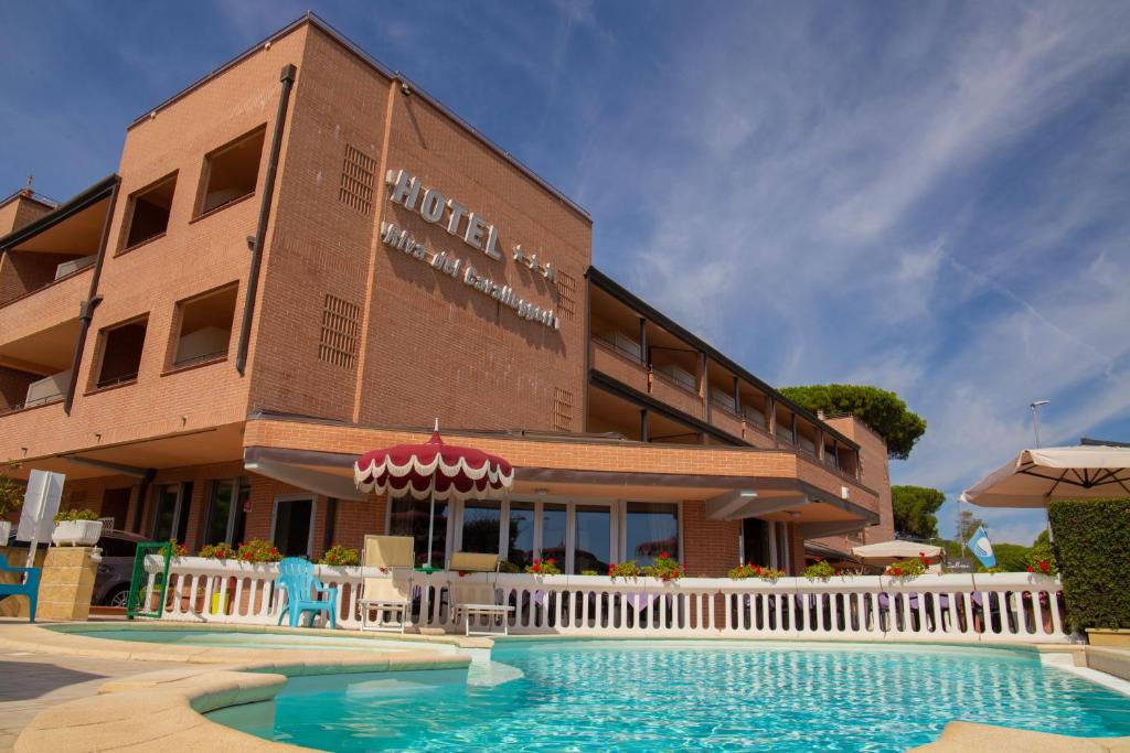 ein Hotel mit einem Pool vor einem Gebäude in der Unterkunft Hotel Riva dei Cavalleggeri in Marina di Bibbona