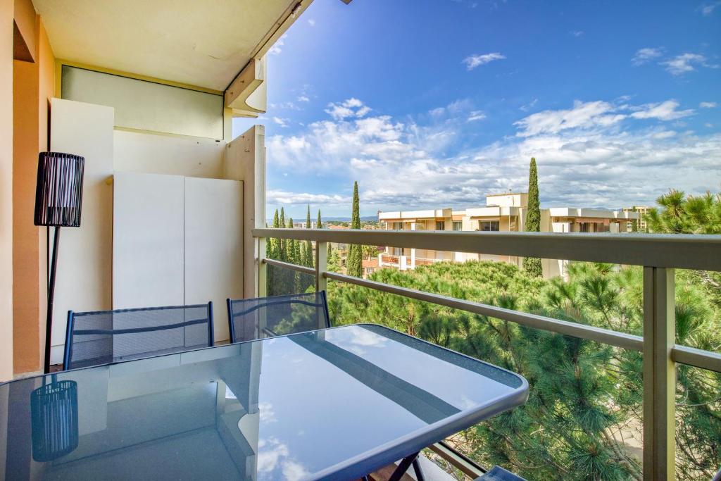 d'une table et de chaises en verre sur un balcon avec vue. dans l'établissement La Lauve - Studio climatisé avec piscine partagée, à Saint-Raphaël