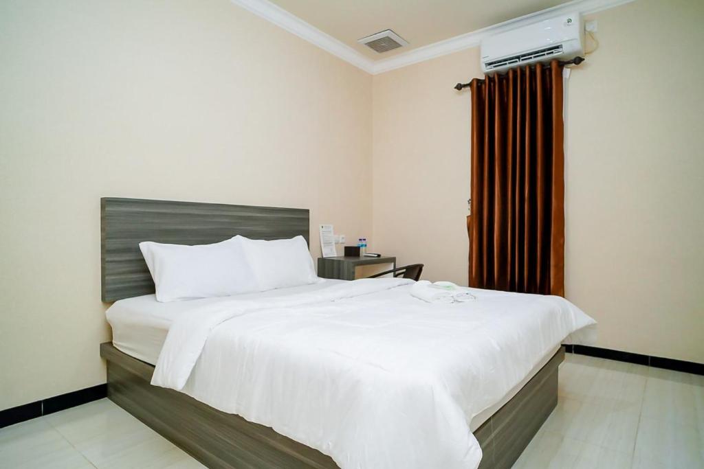 Un dormitorio con una gran cama blanca y una ventana en Mess Rejeki Redpartner en Sampit