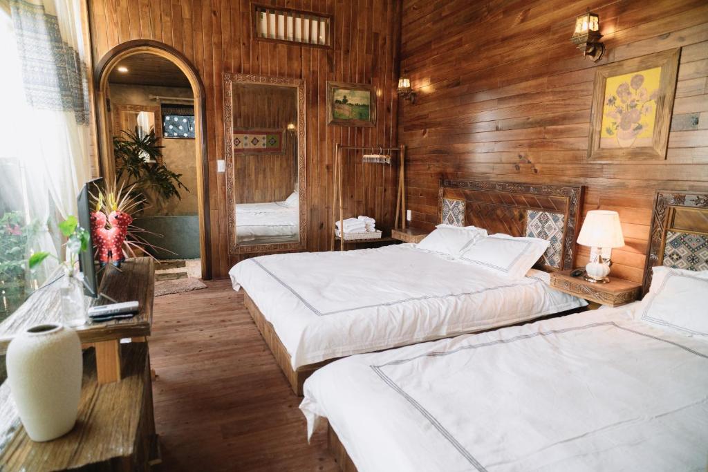 two beds in a room with wooden walls at Mộc Châu Harmony in Mộc Châu