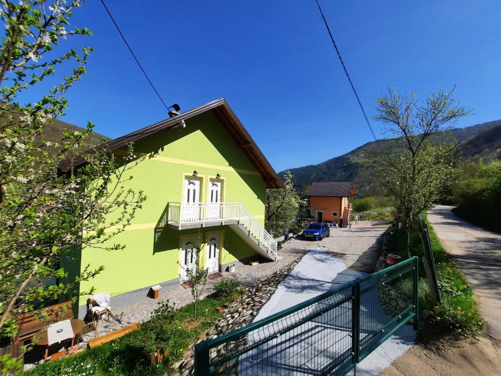 a green house with a balcony on a street at Apartmani Vila na Drini in Foča