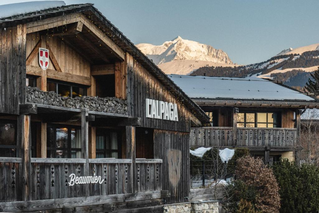 a large wooden building with mountains in the background at L'Alpaga, a Beaumier hotel in Megève