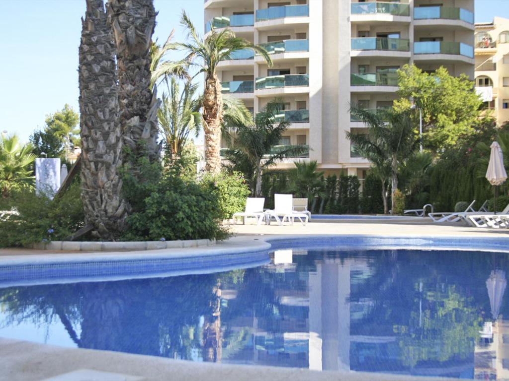 une piscine en face d'un grand bâtiment dans l'établissement Apartamentos Esmeralda Suites Unitursa, à Calp