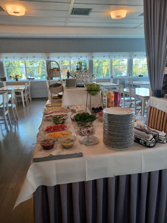 einen langen Tisch mit Teller mit Lebensmitteln drauf in der Unterkunft Mäntyluodon Hotelli in Pori