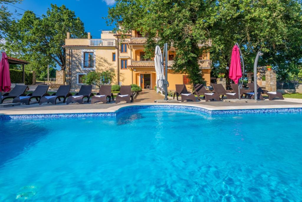 einen Pool mit Stühlen und Sonnenschirmen vor einem Haus in der Unterkunft Villa Tupljak, luxury and comfort in a hidden summer hideout in Gromnik