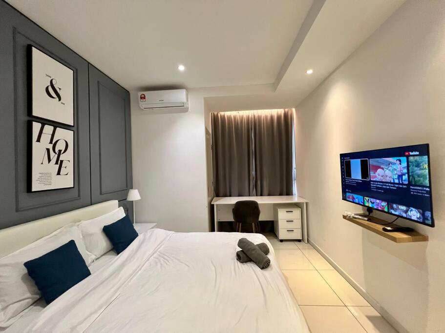 a bedroom with a white bed and a flat screen tv at The Urban Left at Horizon Suites KLIA in Kampong Melot