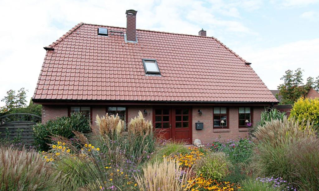 a house with a red roof in a garden at Kleines Nest in Westerrönfeld