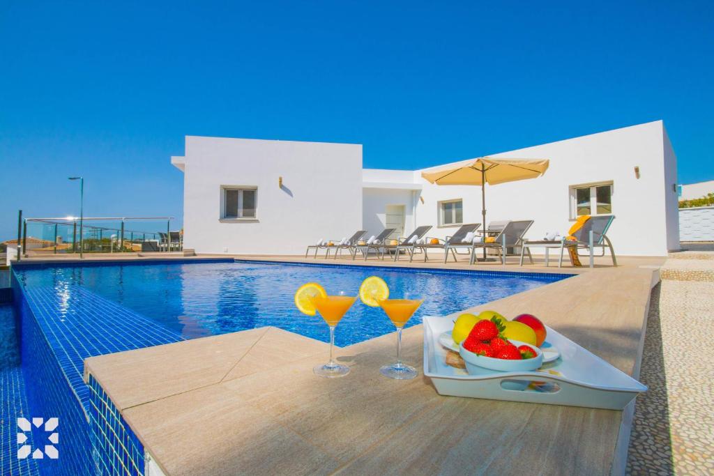 ein Tablett mit Obst und zwei Gläsern neben einem Pool in der Unterkunft Villa Baydal by Abahana Villas in Benissa