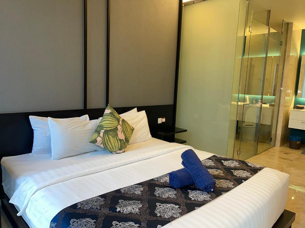 um quarto com uma cama com lençóis brancos e almofadas em Tropicana The Residences By RS em Kuala Lumpur