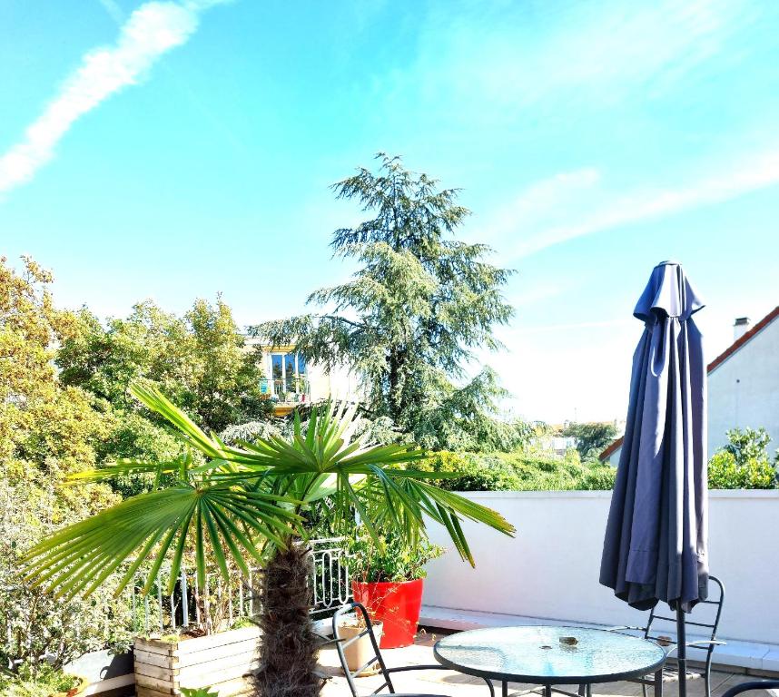 een patio met een tafel en een parasol bij Chambre avec mezzanine dans une maison d'artiste in Rueil-Malmaison