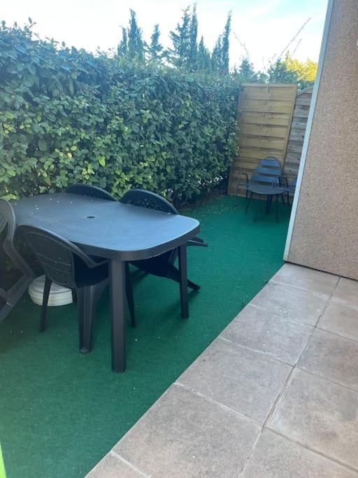 une table et des chaises assises sur une pelouse verte dans l'établissement Jolie appartement dans résidence avec piscine, à Carnoux-en-Provence