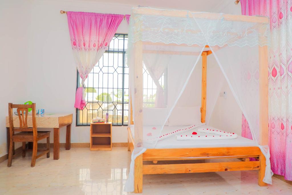 1 dormitorio con cama, escritorio y ventana en Raha house en Nungwi