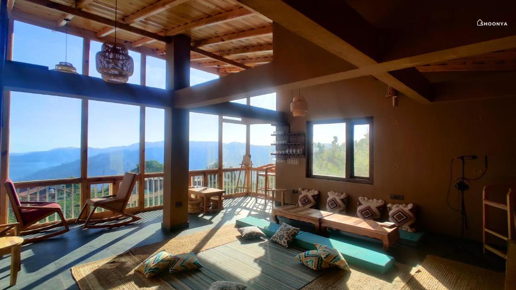 a living room with a view of the mountains at Shoonya Mukteshwar in Mukteswar