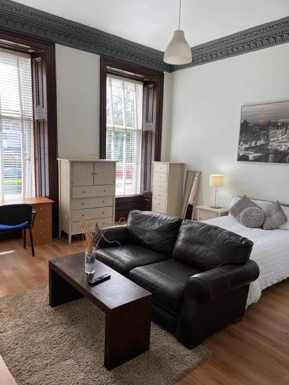 - un salon avec un canapé en cuir noir et un lit dans l'établissement STUDIO APARTMENT PAISLEY ROAD WEST, à Glasgow