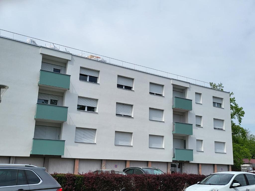 a white apartment building with cars parked in front of it at F2 möblierte 2,5 Zimmer - Wohnung 60 m2 in Saint-Louis