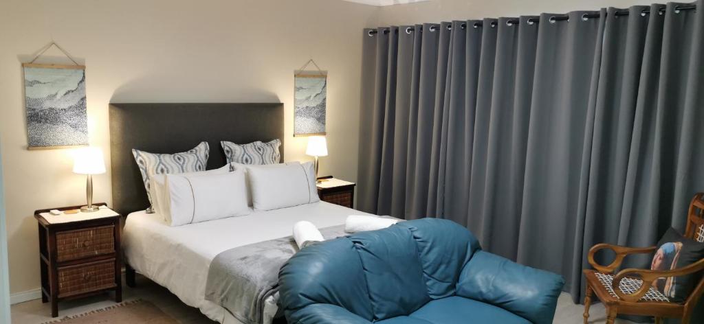 a bedroom with a bed and a blue chair at Mila's at Panorama in Cape Town