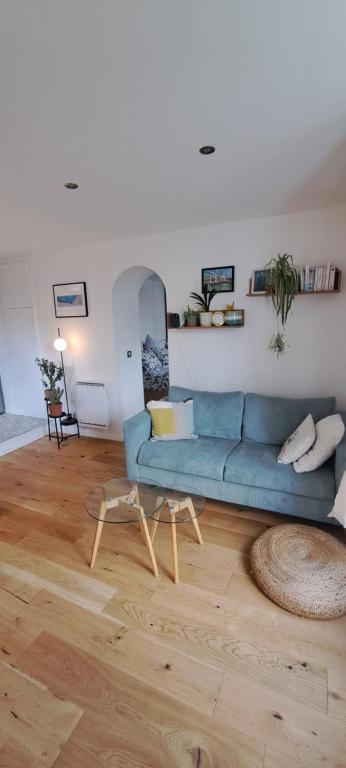 ein Wohnzimmer mit einem blauen Sofa und Holzboden in der Unterkunft Charming appartment near public transport in Suresnes