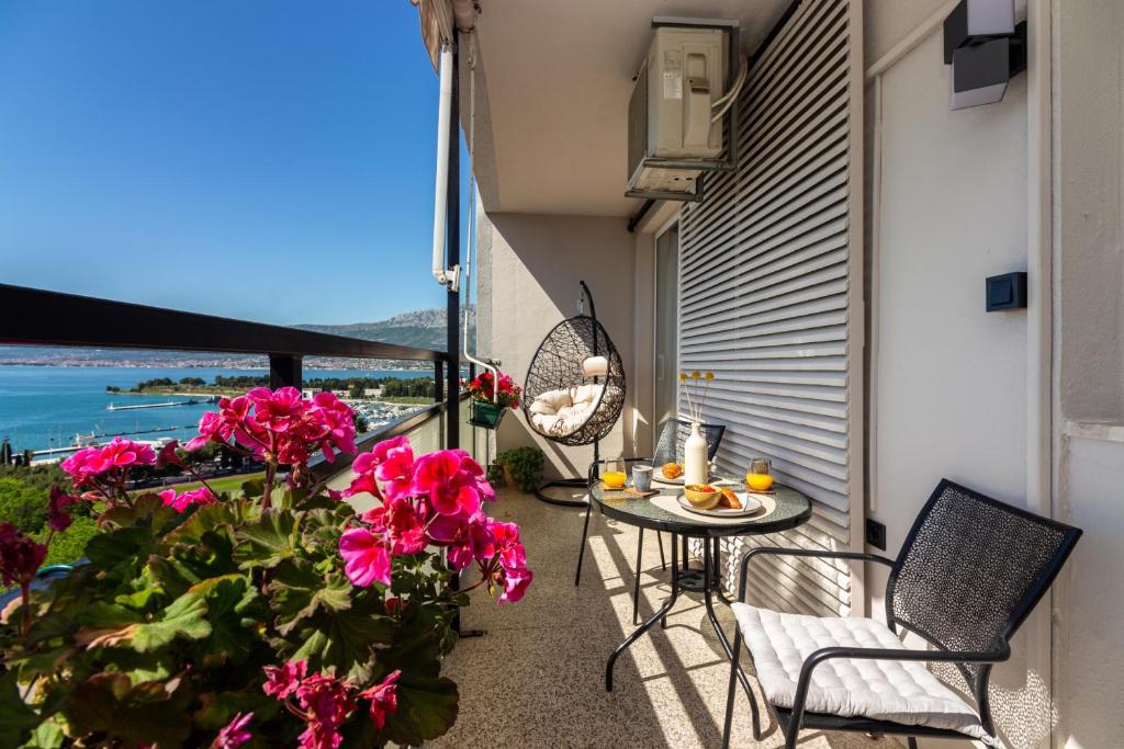 a balcony with pink flowers and a table and chairs at Cozy apartment with a beautiful view in Split