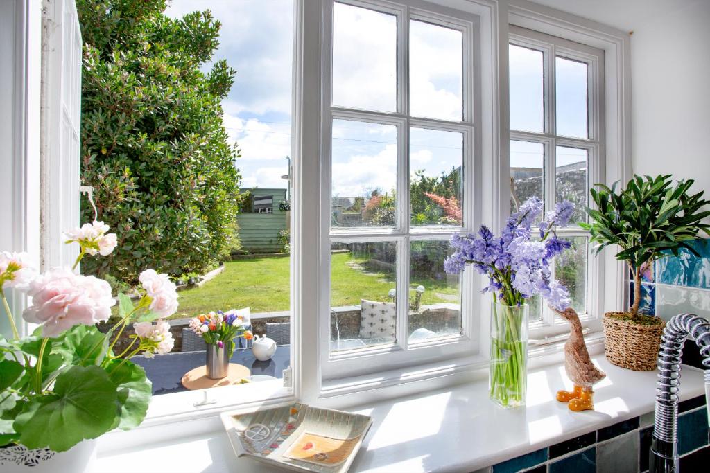 ein Fenster mit Blumenvasen auf einer Theke in der Unterkunft Peacehaven Cottage - Sidmouth in Sidbury