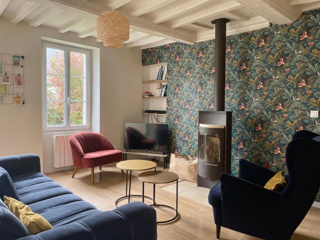 een woonkamer met een blauwe bank en een open haard bij La maison des Declos avec parking privé in Bayeux