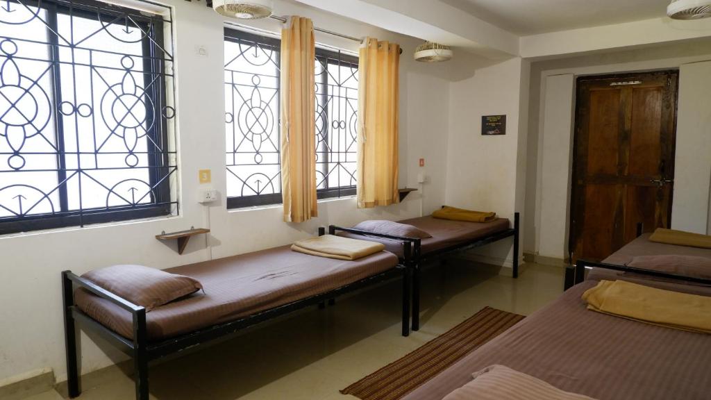 two beds in a room with two windows at BunkNBrew in Palolem
