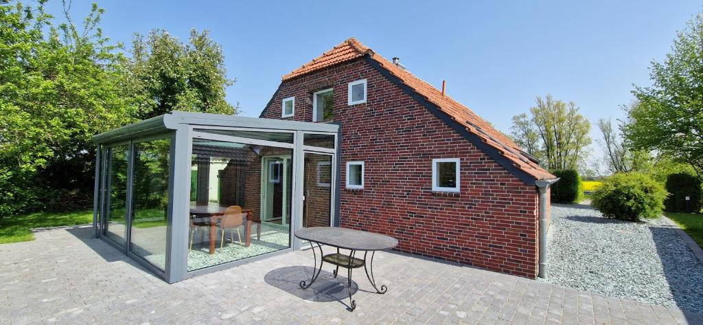 Una casa de cristal con una mesa delante. en Nr 150 - Ferienhaus An't Deep, en Neufunnixsiel