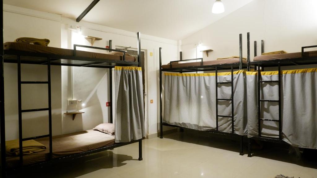 a room with three bunk beds in a room at BunkNBrew in Palolem