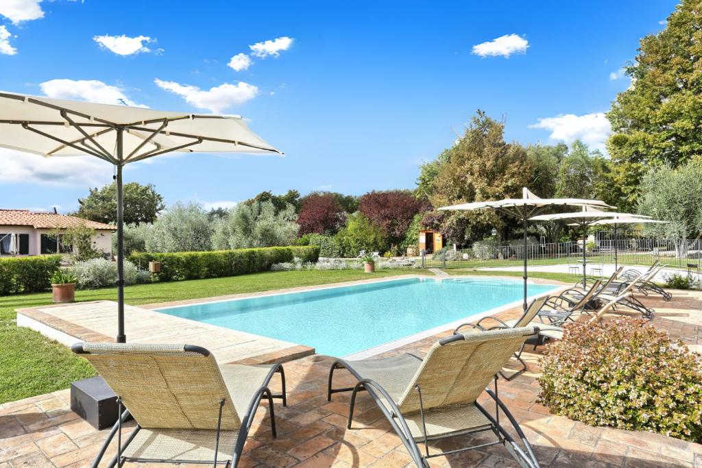 una piscina con sillas y sombrillas en un patio en I Sicomori - Seme di Carota - Glamping e appartamenti con piscina a Saturnia en Saturnia