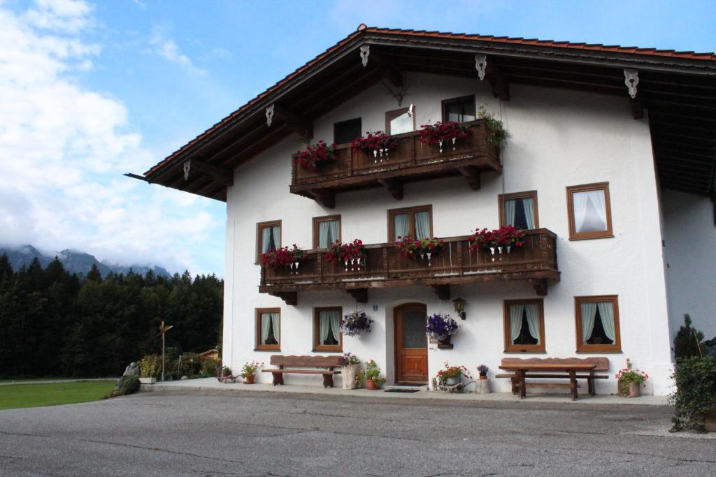 - un bâtiment blanc avec 2 balcons et 2 bancs dans l'établissement Ferienwohnung Hinterpommern - Chiemgaukarte, à Inzell