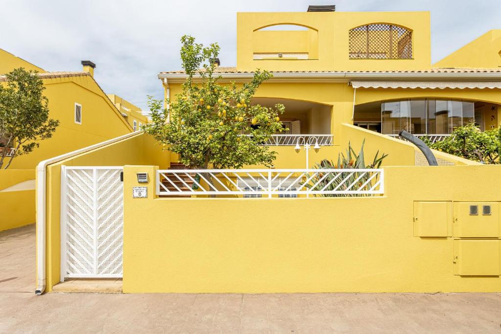 a yellow house with a white gate at Family house on the beach for holidays and temporary workers at Beach Sagunto Valencia in Sagunto